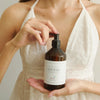 Woman holding a bottle of hand wash with a plain background