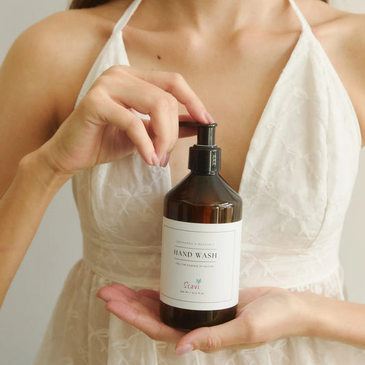 Woman holding a bottle of hand wash with a plain background